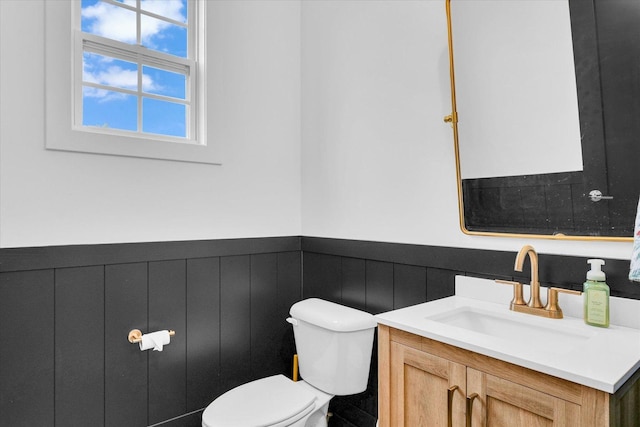 bathroom featuring a wainscoted wall, vanity, and toilet