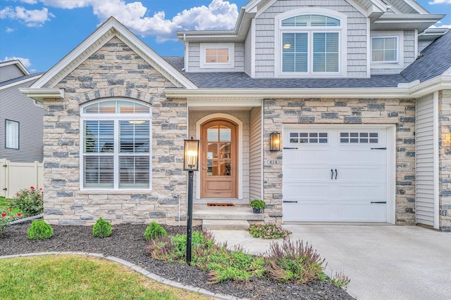 view of front facade featuring a garage, concrete driveway, a shingled roof, and stone siding