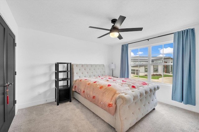 bedroom with light carpet, a textured ceiling, a ceiling fan, and baseboards