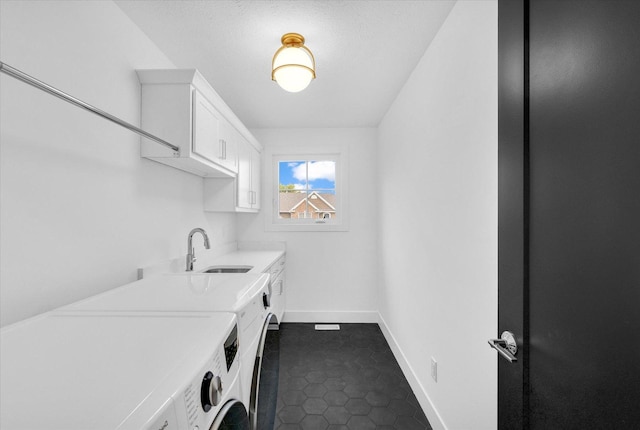 washroom featuring washing machine and dryer, dark tile patterned flooring, a sink, baseboards, and cabinet space