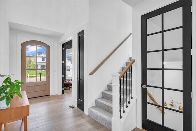 foyer with light wood-type flooring, stairs, and visible vents