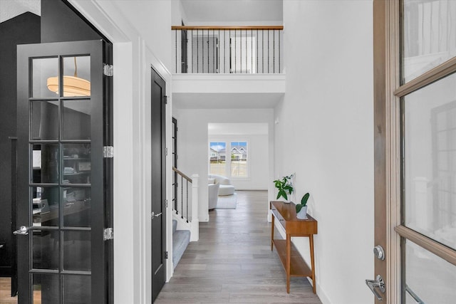 foyer featuring a high ceiling, stairway, wood finished floors, and baseboards