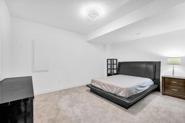 bedroom featuring light colored carpet, a textured ceiling, and baseboards