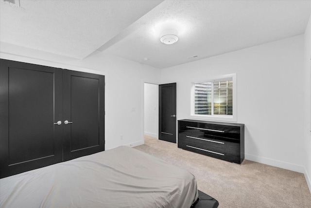 bedroom with light carpet, a textured ceiling, and baseboards