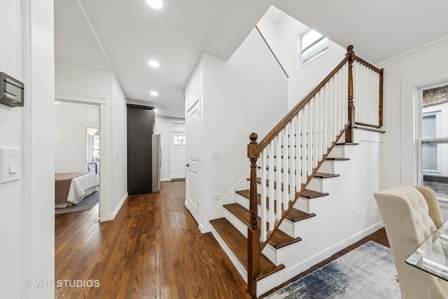 stairs with hardwood / wood-style floors and ornamental molding