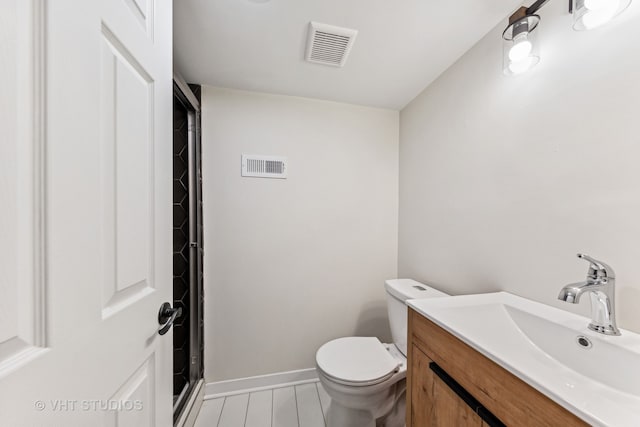 bathroom with walk in shower, vanity, and toilet