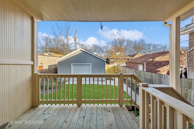 wooden terrace with a lawn, a garage, and an outbuilding