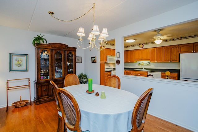 dining room featuring sink, hardwood / wood-style floors, and ceiling fan with notable chandelier