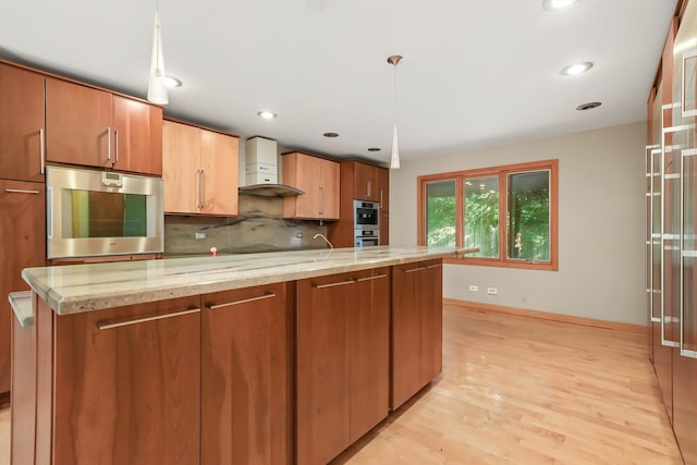 kitchen featuring tasteful backsplash, light stone counters, light hardwood / wood-style flooring, and hanging light fixtures