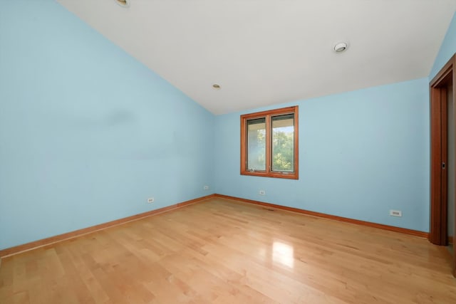 empty room featuring light wood-type flooring and vaulted ceiling