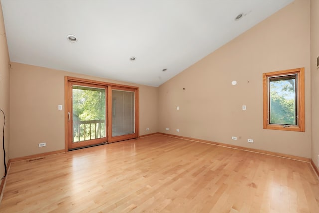 empty room with high vaulted ceiling and light hardwood / wood-style flooring