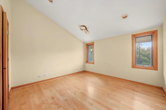 spare room featuring light hardwood / wood-style flooring and lofted ceiling