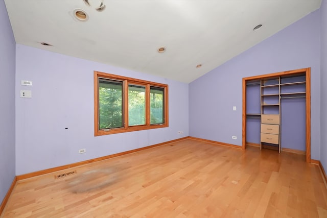 unfurnished bedroom with light wood-type flooring, a closet, and lofted ceiling