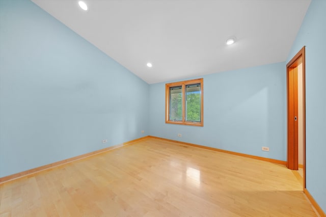 spare room featuring lofted ceiling and light wood-type flooring