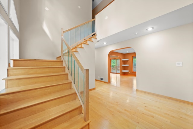 stairs featuring wood-type flooring and a high ceiling