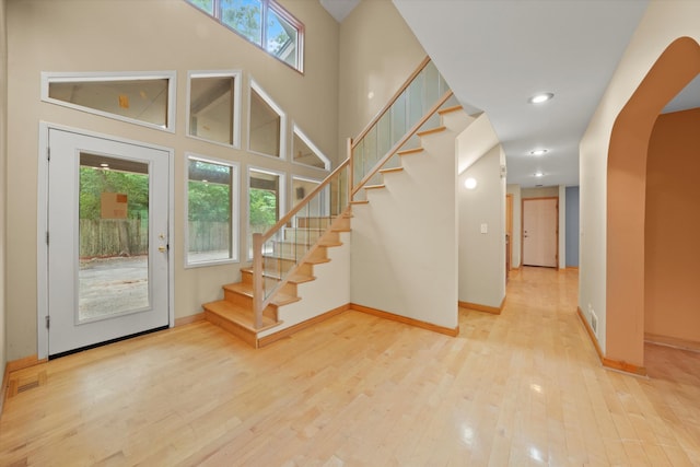 entryway with light hardwood / wood-style flooring and a towering ceiling