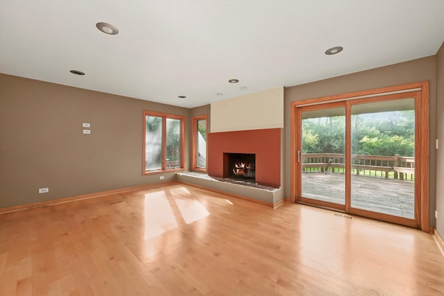 unfurnished living room featuring plenty of natural light and light hardwood / wood-style flooring