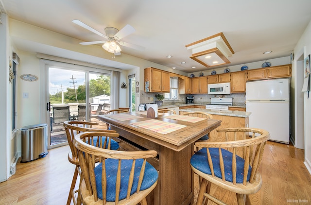 kitchen featuring decorative backsplash, white appliances, light hardwood / wood-style floors, and sink