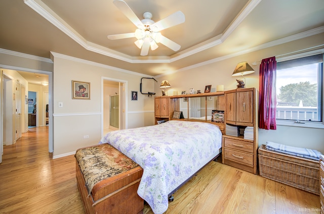 bedroom with a tray ceiling, ceiling fan, crown molding, and light wood-type flooring