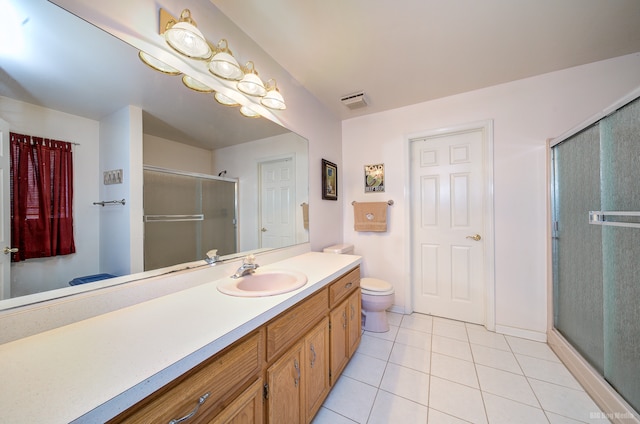 bathroom featuring tile patterned flooring, vanity, a shower with shower door, and toilet