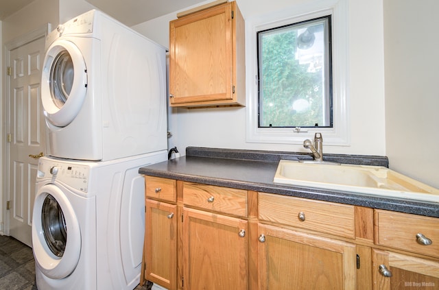 clothes washing area featuring sink, cabinets, and stacked washer / drying machine