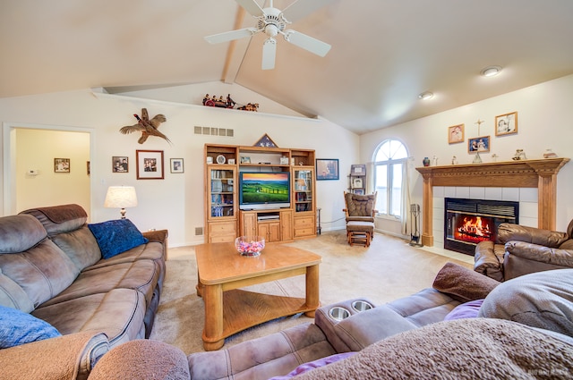 living room with ceiling fan, light colored carpet, a tile fireplace, and vaulted ceiling