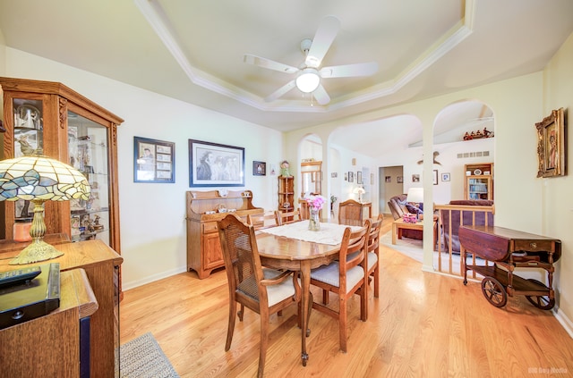 dining space with a raised ceiling, ceiling fan, crown molding, and light hardwood / wood-style floors