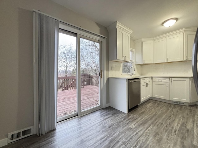 kitchen with backsplash, stainless steel dishwasher, sink, light hardwood / wood-style flooring, and white cabinets