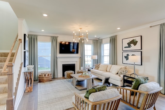 living room with a chandelier, ornamental molding, and light wood-type flooring