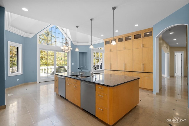 kitchen with stainless steel dishwasher, dark stone counters, sink, pendant lighting, and a center island with sink