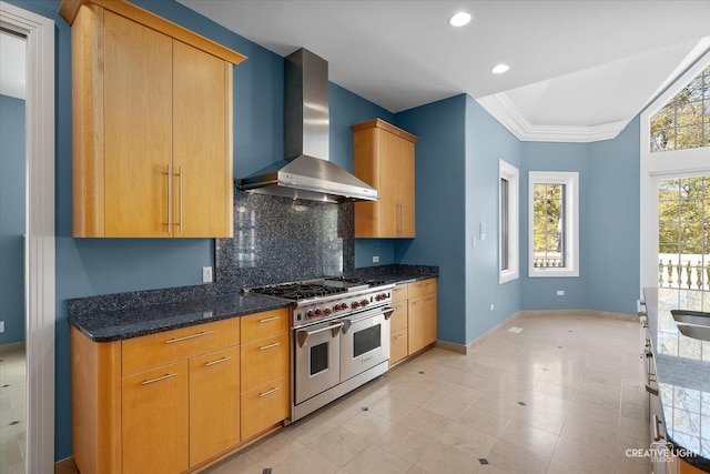 kitchen featuring a healthy amount of sunlight, range with two ovens, wall chimney range hood, and tasteful backsplash