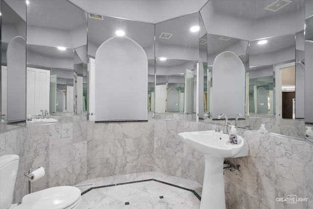 bathroom with toilet and tile walls