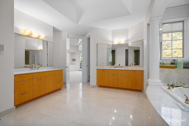 bathroom with a relaxing tiled tub, ornate columns, and vanity