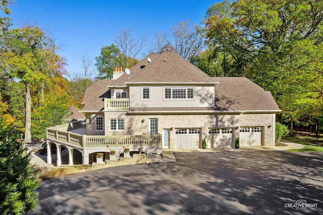 back of house with a balcony, a deck, and a garage