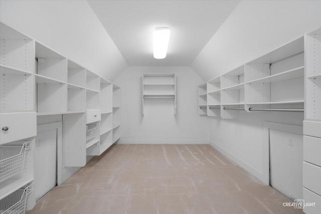 spacious closet with light colored carpet and lofted ceiling