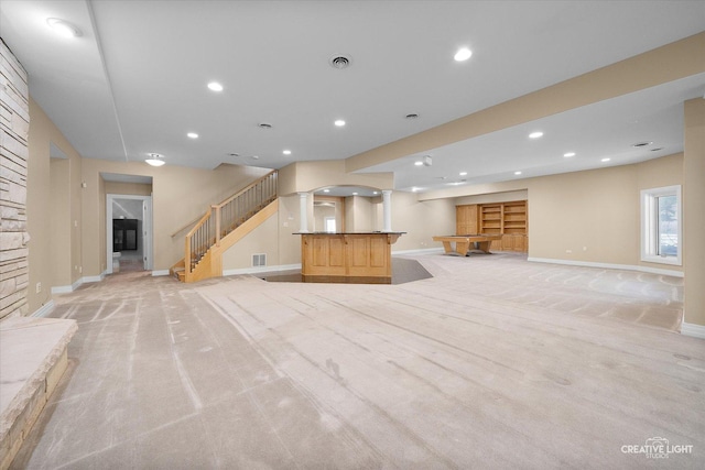 unfurnished living room with a stone fireplace and light colored carpet