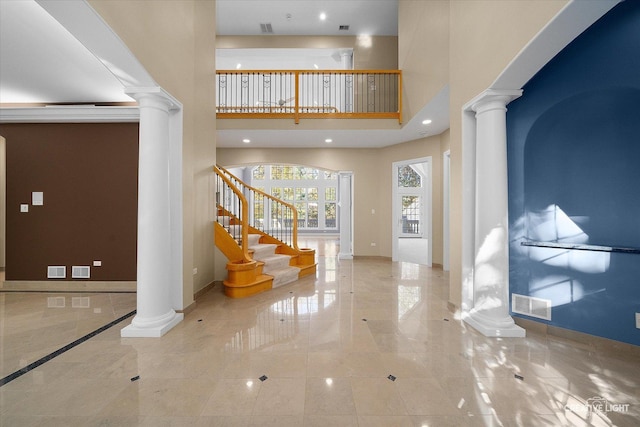 foyer entrance featuring a towering ceiling and decorative columns