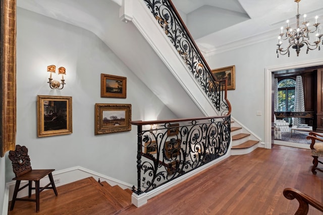 stairway featuring hardwood / wood-style floors, lofted ceiling, ornamental molding, and a chandelier