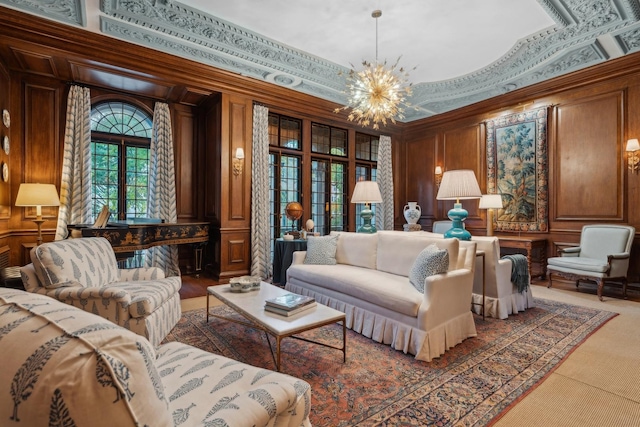 living room featuring a high ceiling, wooden walls, an inviting chandelier, and ornamental molding