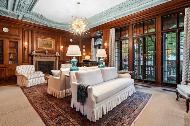 sitting room with a notable chandelier, ornamental molding, carpet floors, and wooden walls