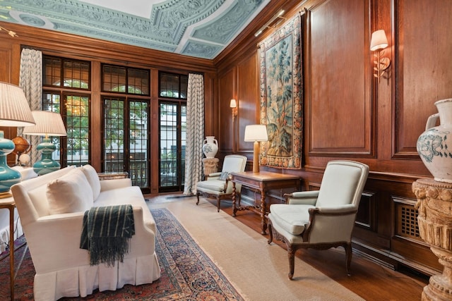 living area featuring wood walls, wood-type flooring, and ornamental molding