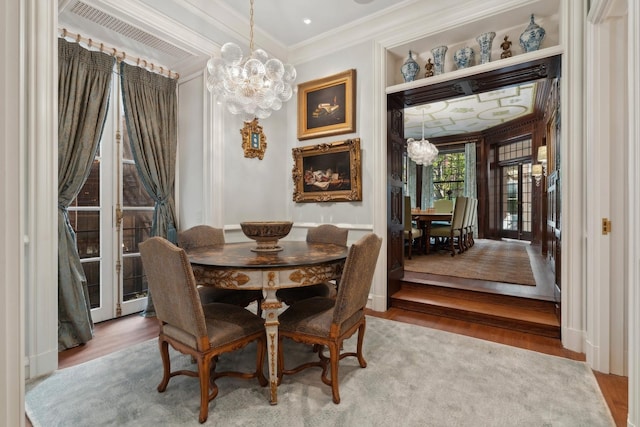 dining space with ornamental molding, a notable chandelier, and hardwood / wood-style flooring