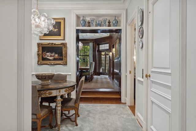 hall featuring crown molding, a chandelier, and light wood-type flooring