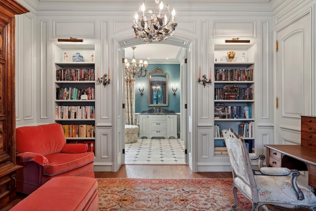 office featuring a notable chandelier, built in shelves, light wood-type flooring, and ornamental molding