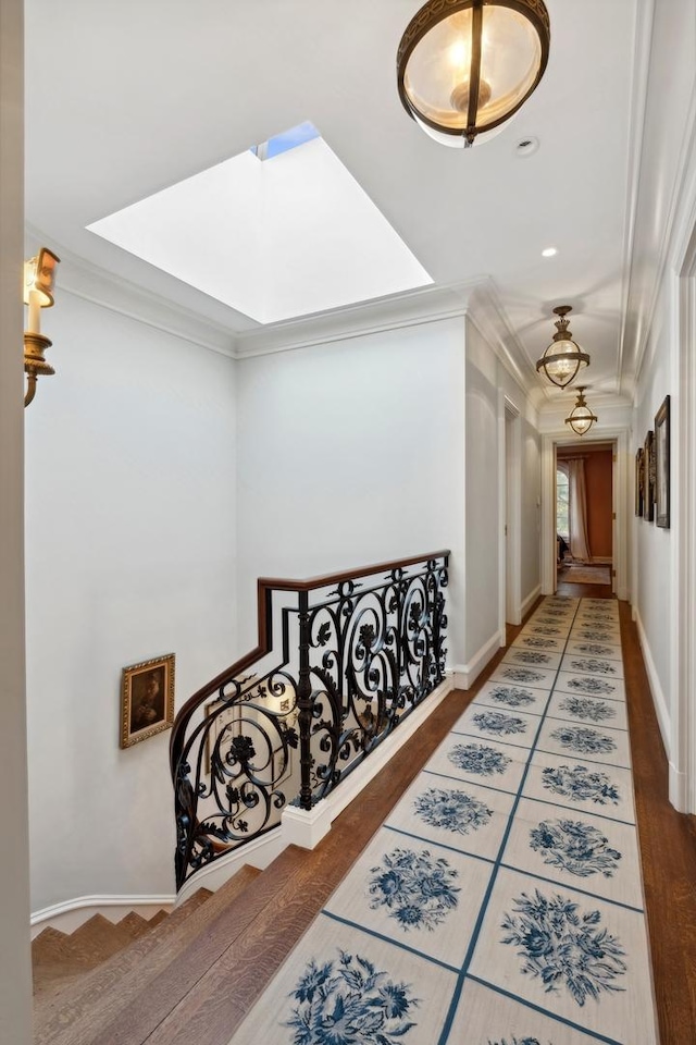 hallway with hardwood / wood-style floors, a skylight, and crown molding