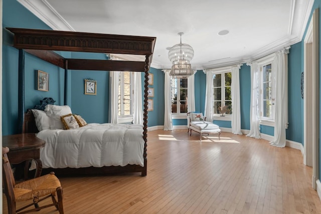 bedroom featuring an inviting chandelier, light hardwood / wood-style flooring, multiple windows, and crown molding