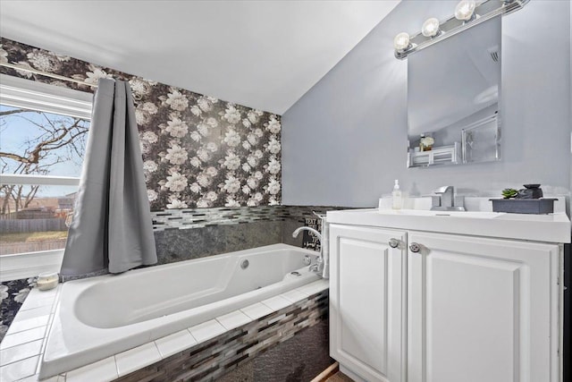 bathroom featuring vanity, lofted ceiling, and tiled tub