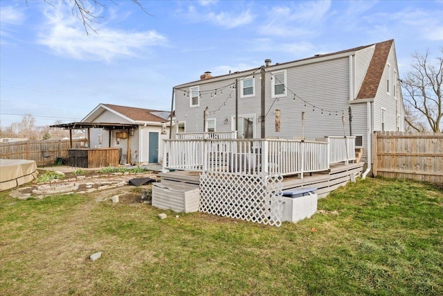 back of house with a deck and a lawn