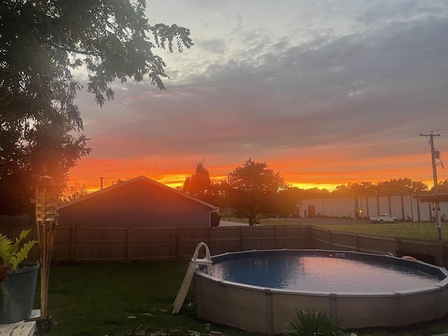 pool at dusk featuring a lawn