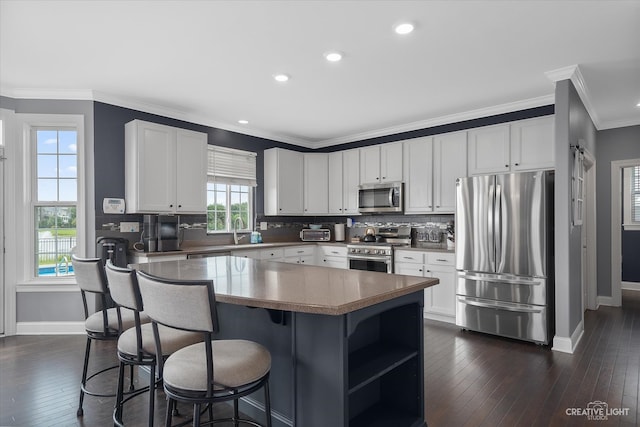 kitchen with crown molding, dark hardwood / wood-style flooring, white cabinets, and stainless steel appliances